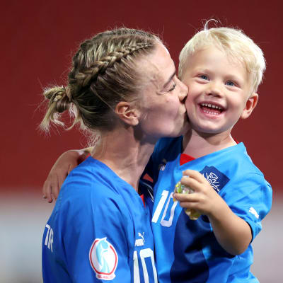 Dagny Brynjarsdottir suutelee poikaansa kentällä viimeisen EM-ottelun jälkeen.