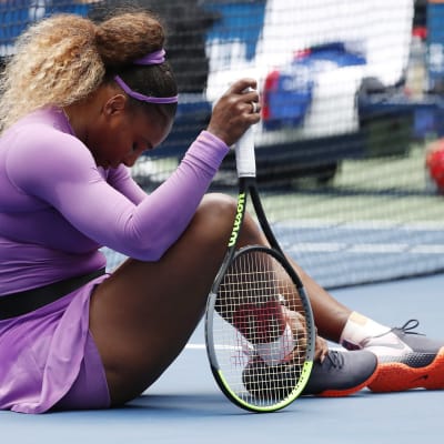 Serena Williams sitter på planen och håller om sin vrist.