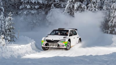 En vit rallybil kör i snö.