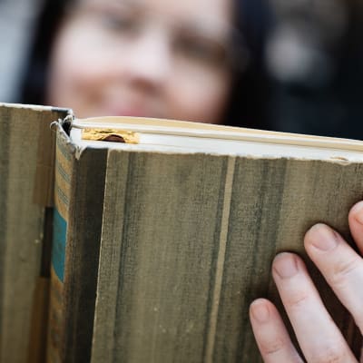En gammal bok hålls i med en hand.
