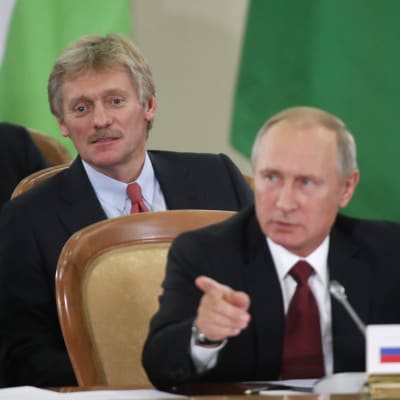 Putins talesman Dmitrij Pdeskov strax bakom president Putin under en konferens i Sotji den 11 oktober 2017.