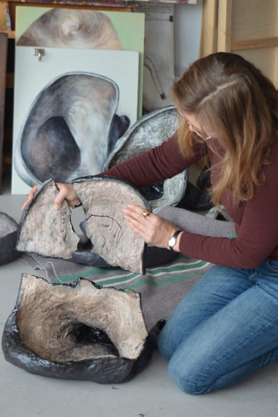 Bildkonstnären Magdalena Åberg håller upp bitarna till ett konstverk i keramik som spruckit