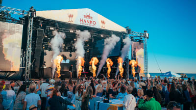 Festival vid vattnet i Hangö. Pyroteknik på scen och glada människor i publiken.