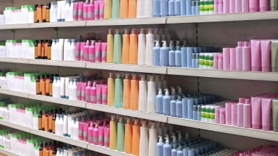 Omärkta tvål- och schampoflaskor i olika färger står radade på hyllor.