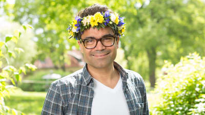 Ståuppkomiker David Battra med blomsterkrans i håret.
