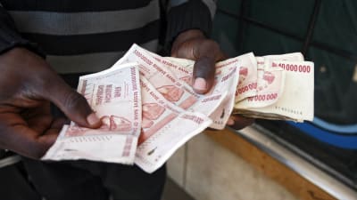En man håller zimbabwiska dollarsedlar