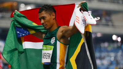 Sprinter håller upp den sydafrikanska flaggan efter guldlopp.