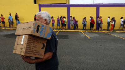 Folk står i kö för att få matlådor i Puerto Rico.