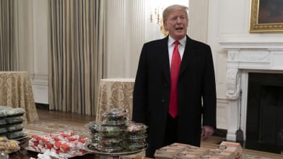 Preisdent Trump bakom ett bord fullt av hamburgare som serverades åt fotbollslaget Clemson Tigers i Vita huset