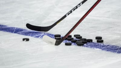 Klubbor och puckar i en hockeyrink.