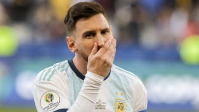 Lionel Messi håller för sin mun.