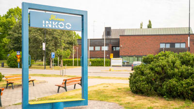 Ingå kyrkby sommaren 2023. Kommungården i bakgrunden (ett rött tegelhus) och en fotoskylt som föreställer en stor blå ram med texten "Iloinen Inkoo".