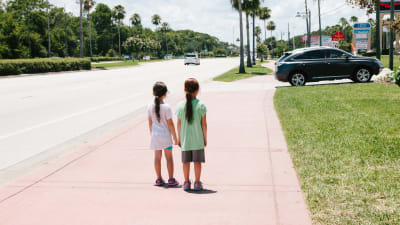 Två flickor står ensamma på gatan.
