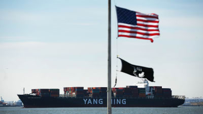 Kinesiskt fullastat continerfartyg anländer till New Yorks hamn. USA:s flagg i förgrunden.