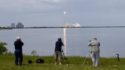 Fotografer på strand ser uppskjutning av Falcon 9-bärraketen i stort rökmoln på Cape Canveral