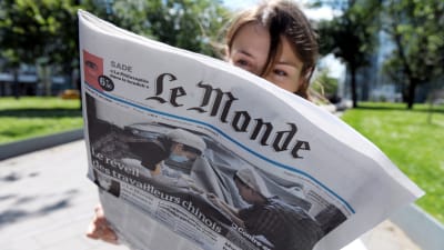 Kvinna läser franska dagstidningen Le Monde.