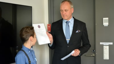 En pojke tar emot ett diplom av en medelålders man.