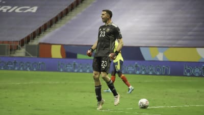 Emiliano Martinez hoppar och jublar efter en straffräddning. 