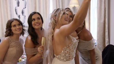 En grupp kvinnor i bröllopsklänningar tar en selfie. 