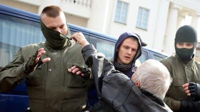 Kvinna försöker riva av masken på en man som griper demonstranter  12.9.2020 i Minsk, Belarus