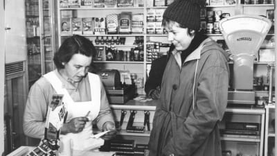En butiksinnehavare och en kund i en bybutik 1960-talet.