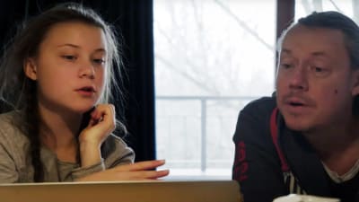 På bilden syns Greta och pappa Svante Thunberg. De sitter vid ett bord med en dator framför sig och pratar. 
