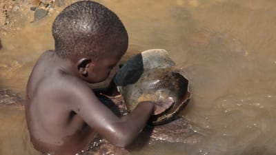 Pieni lapsi huuhtoo kultaa joessa Zimbabwessa.