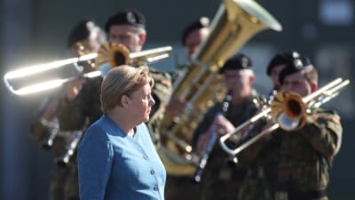 Angela Merkel står framför en militärorkester.