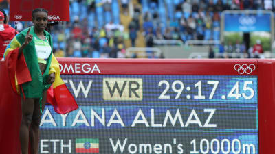 Almaz Ayana bredvid en skylt med världsrekordtiden.