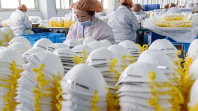 Munskydd på rad och fabriksanställda som konrollerar munskydd i Kina.
