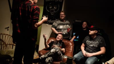 Ynglingar står runt Sami Heinonen i ett mörkt rum.