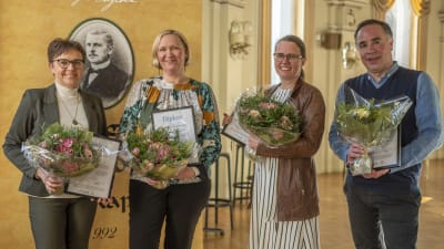 Fyra personer står på rad och håller i diplom och blommor medan de tittar in i kameran. Från vänster: Annica Törmä, Tiina Sjelvgren, Jenny Sylvin och Jens Berg.