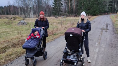 Sara och Erika står på en väg med sina barn i vagn.