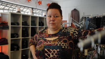 Erica Wickman står bredvid e n klädställning i sin butik