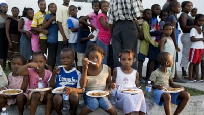 Haitiska barn sitter och äter