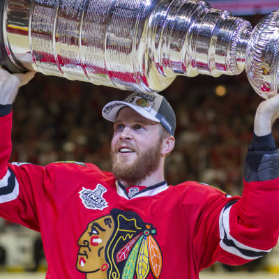 Rödklädd ishockeyspelare håller Stanley Cup-pokalen över huvudet.