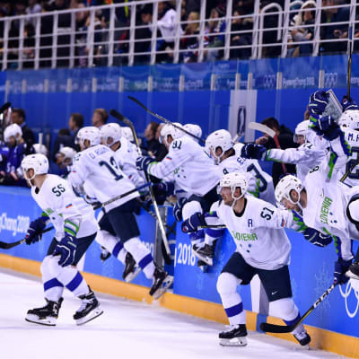 Sloveniens hockeylandslag rusar ut ur spelarbåset för att fira seger.