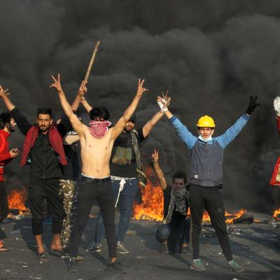 Unga irakiska demonstranter visar segertecknet mitt under sammandrabbningar med kravallpolis i Bagdad på måndagen. 