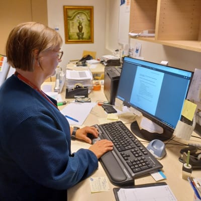 En kvinna på ett kontor sittandes framför sin dator