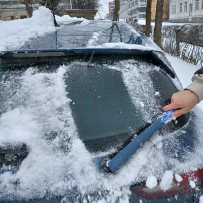 En vindruta på en bil skrapas fri från snö