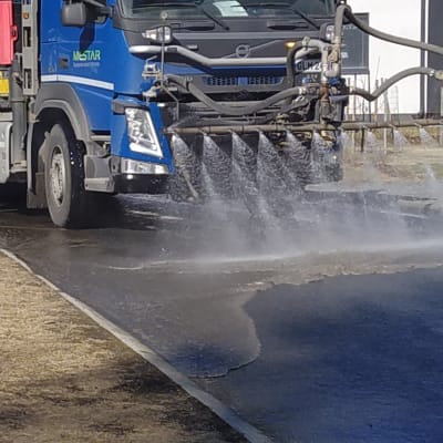 Tankkiauto pesee kadusta talven hiekoituspölyä