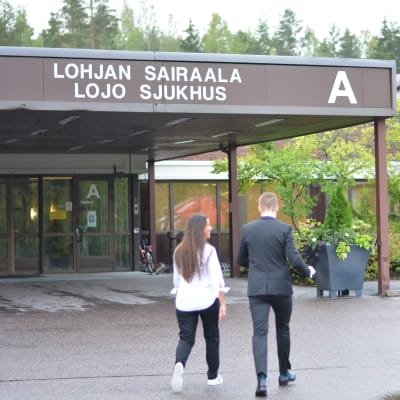 Två personer går in via huvudingången till Lojo sjukhus