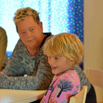 Raul Carusi, 6 år, sitter vid ett bord tillsammans med barnträdgårdslärarna Valborg Vilhjalmsdottir och Heidi Kihlstedt på Solbacka daghem i Karis,