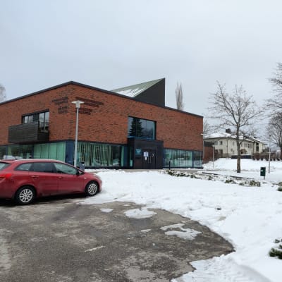 En byggnad i mörkt rött tegel med mycket fönster. Där finns Ingå bibliotek och Ingå kommunhus.