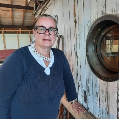 En kvinna med mörka kläder står intill kajutan på ett gammalt fartyg