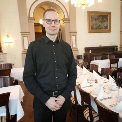 Mustapaitainen ravintoloitsija Henry Olander Finlaysonin Palatsi -ravintolan ruokasalissa.