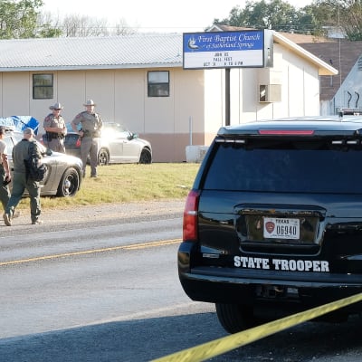 Polisbil och poliser innanför avspärrningen vid brottsplatsen i Sutherland Springs i Texas,