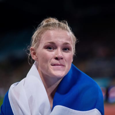 Wilma Murto kietoutuneena Suomen lippuun.