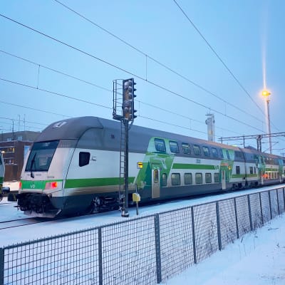 Kaksikerroksinen Intercity-juna Tampereen asemalla. Valkoinen juna, jossa vihreitä raitoja kyljessä. 
