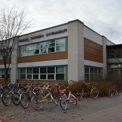Pargas svenska gymnasiums byggnad i ljusa och bruna tegel, med cyklar parkerade utanför.